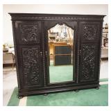 1217	ORNATE CARVED 3 DOOR CABINET WITH BEVELED GLASS CENTER MIRROR AND ADJUSTABLE SHELVES IN AN EBONIZED FINISH, APPROXIMATELY 84 IN X 26 IN X 73 IN H