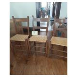 Three wooden chairs with woven seats