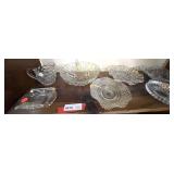 Three shelf lot marked 6018 of assorted glassware to include a deep dish pipe plate, a vintage five part serving dish with embossed fruit, carafe, assorted bowls, and more. See pictures for details.