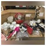Variety of Kitchen items: strainer, cheese board, paper towel holder, measuring cups and spoons, apple slice, can opener, flatware, Utensils, white bowls etc.
