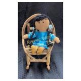 Doll on wooden rocking chair.